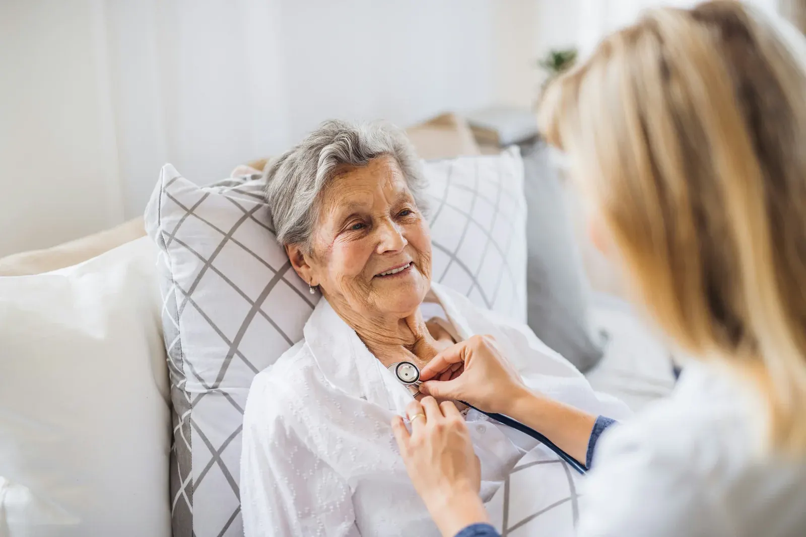 A nurse checking an elderly woman with a stethoscope